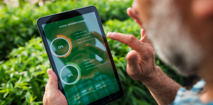 Mann steht im Feld und schaut sich Auswertungen auf einem Tablet an